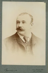 Portrait en buste de Clarence F. Newcomb portant un costume, un gilet et une cravate, avec la tête tournée vers la gauche